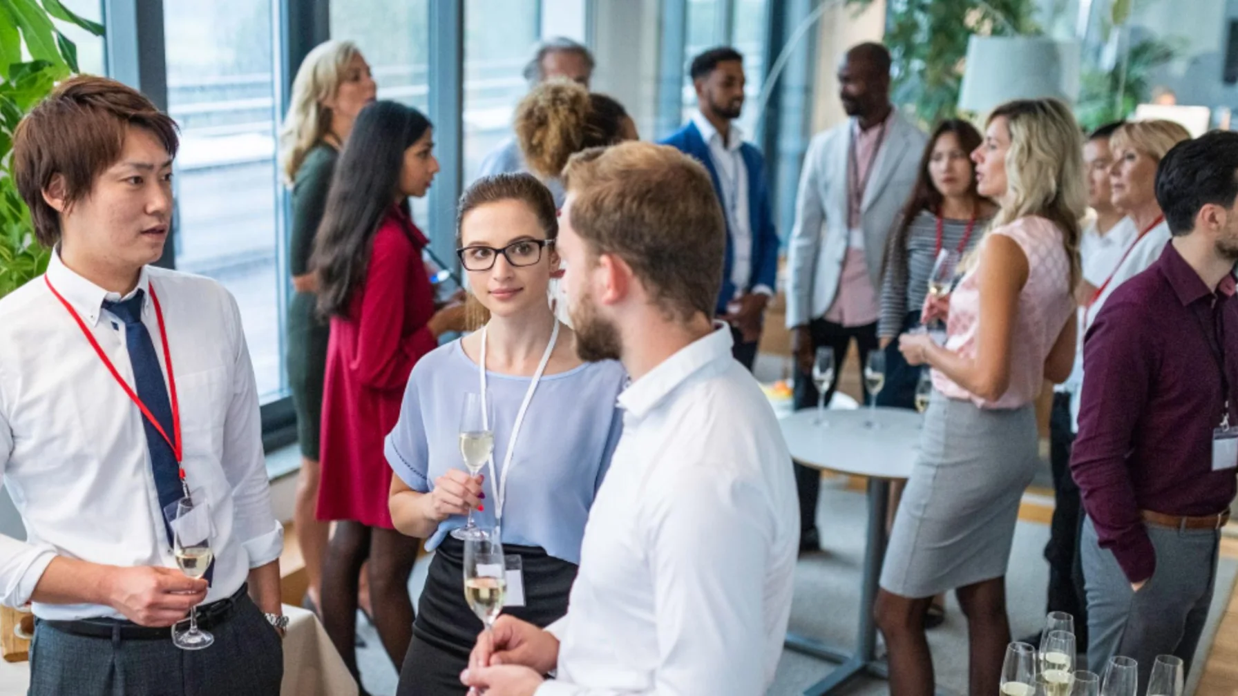 Diverse professional attendees networking over drinks in a bright, polished reception setting