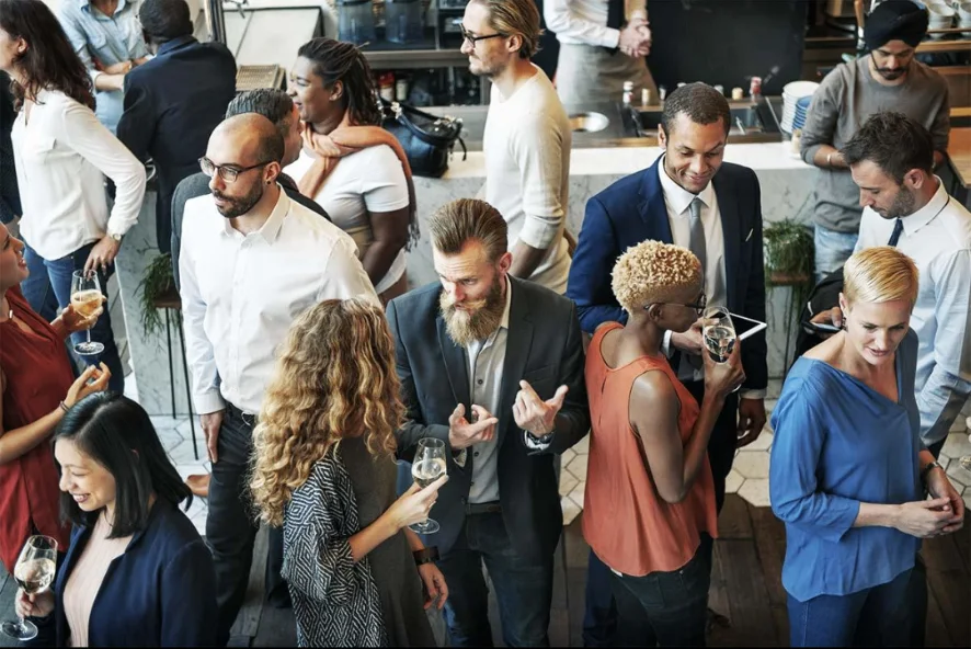 Diverse professionals networking and holding drinks at a community and corporate celebration in an event venue